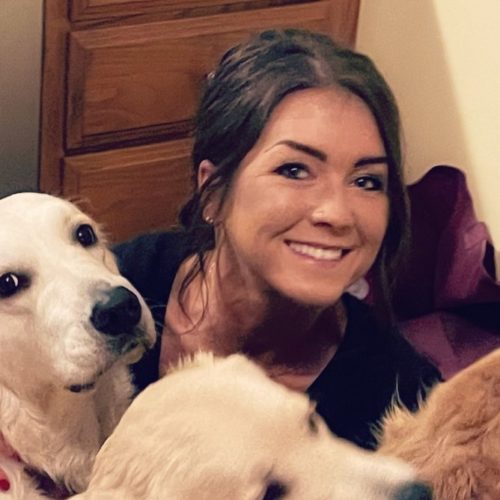 A woman posing with three dogs.