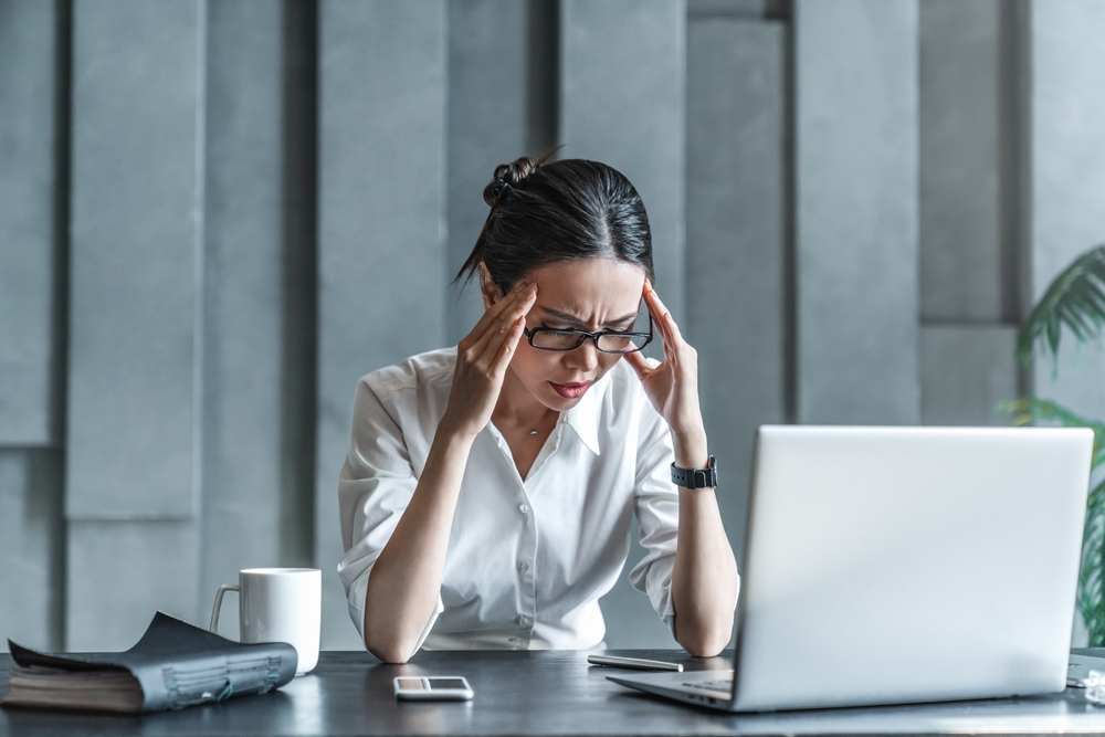 A frustrated insurance agent holds her temples.